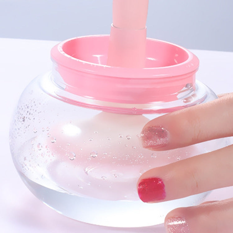 Electric makeup brush scrubber cleaning basin with water and hand holding a brush