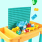 Children's building table toy with teal pegboard panel, yellow tray, and colorful blocks