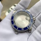 Stainless steel watch case with blue bezel and crown, shown on white cloth