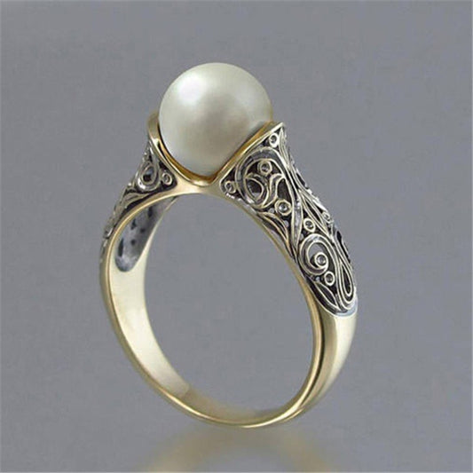 Gold-tone ring with round faux pearl and ornate filigree side setting