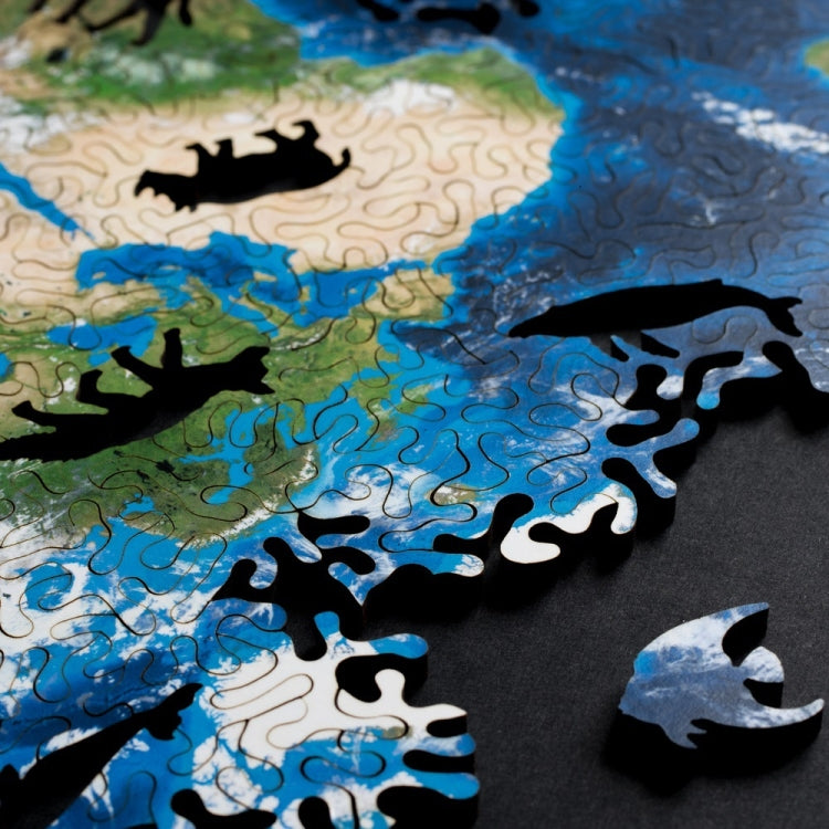 Wooden puzzle close-up with blue ocean area and black animal pieces on board