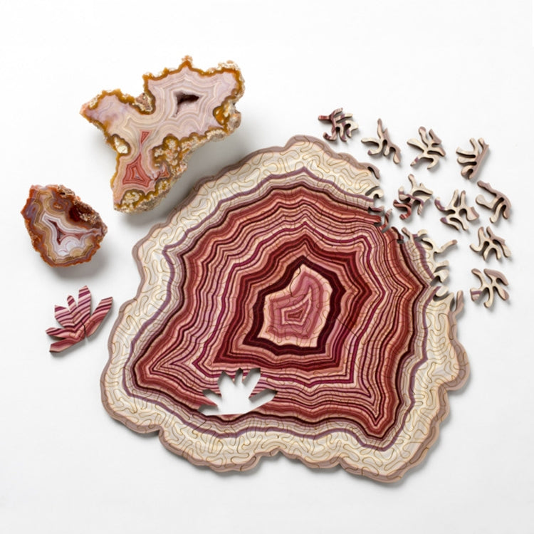 Wooden jigsaw puzzle with pink-and-cream agate-style pattern and scattered pieces