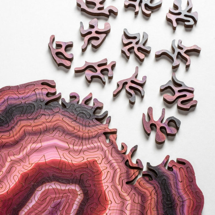 Wooden jigsaw puzzle piece close-up with purple and red agate-style contours