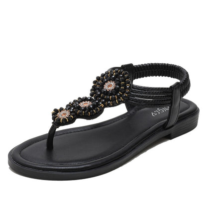 Black flat thong sandals with beaded floral straps and low-profile sole
