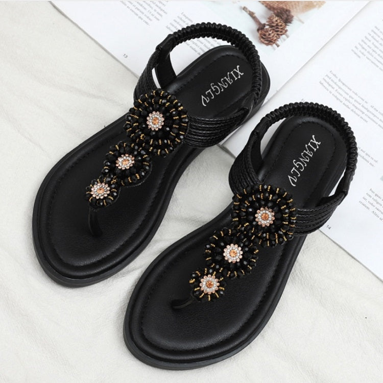 Black flat thong sandals showing beaded floral front strap detail