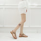 Tan flat thong sandals on feet with jeweled cross straps and open toe