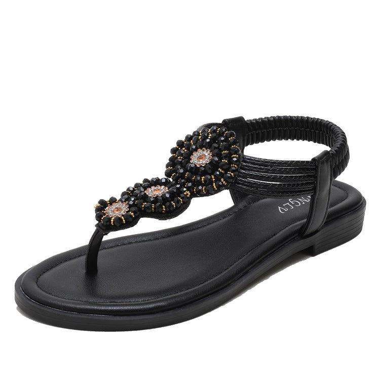 Black flat thong sandals with beaded flower details and thick cushioned sole