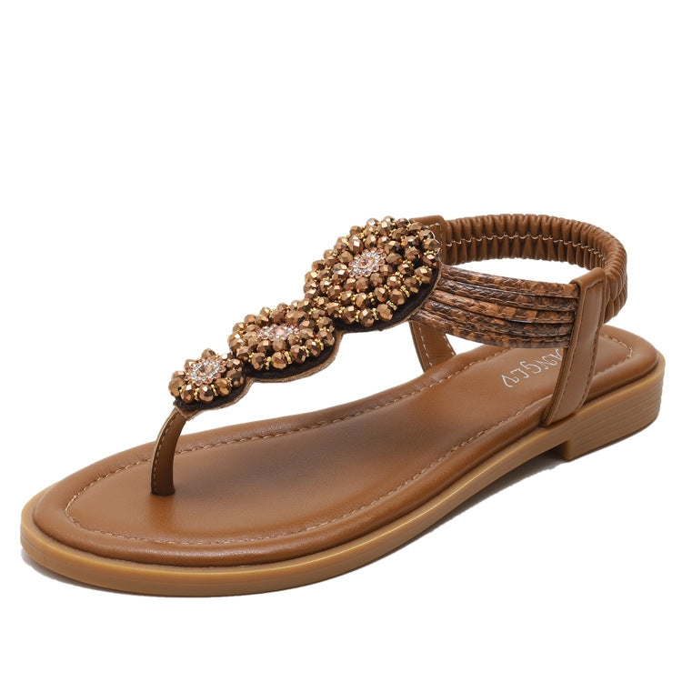 Tan flat thong sandals featuring a ruched ankle strap and jeweled bow detail