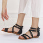 Women's black open-toe wedge sandals on feet, with multiple Roman straps and buckle.