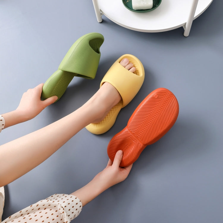 Three plastic slide slippers in green, yellow, and orange with textured soles