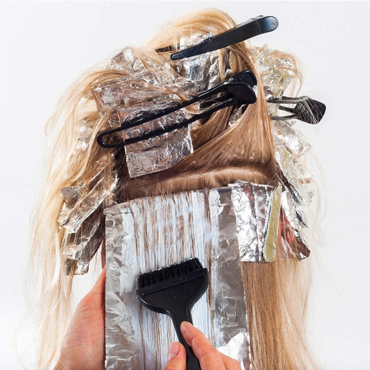 Hair dye brush with combs placed on wrapped hair during application