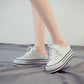 White lace-up canvas platform sneakers with thick sole, side view on feet