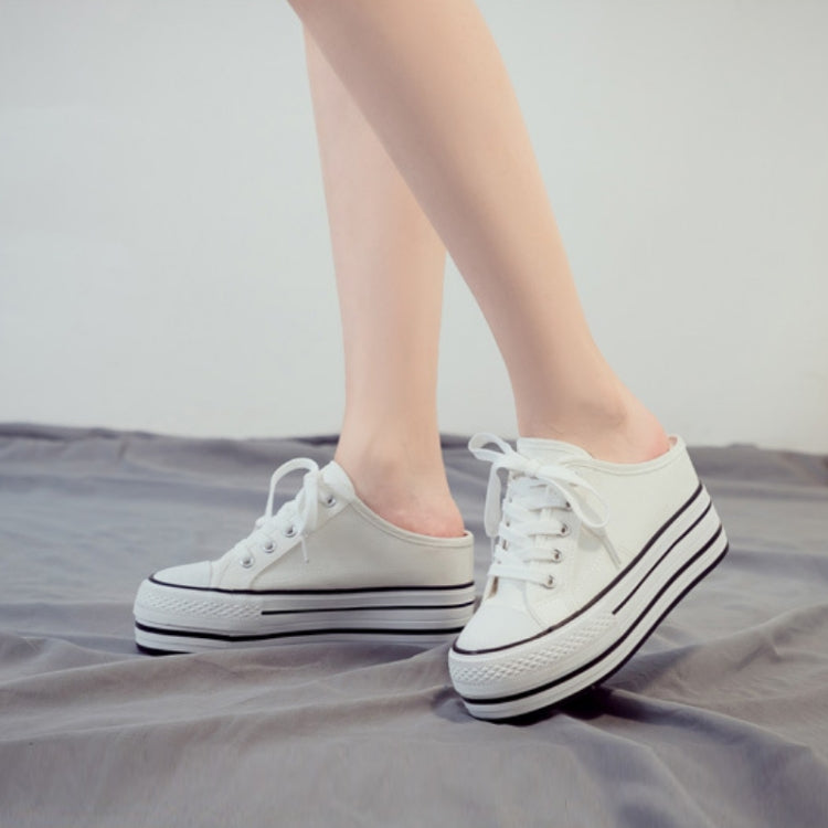 White lace-up canvas platform sneakers with thick sole, side view on feet