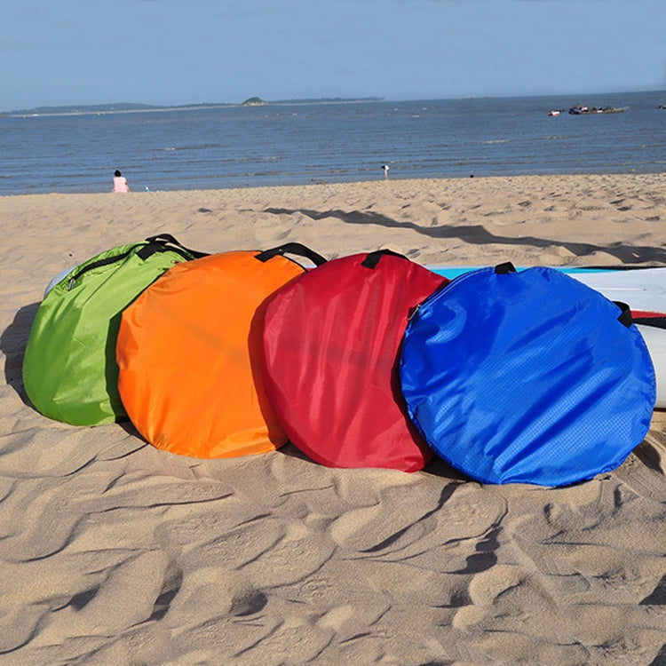 Rolled inflatable paddle board sails in green, orange, red, and blue on sand