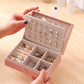 Pink small jewelry storage box open with divided compartments and stud earrings and rings