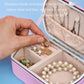 Pink travel jewelry storage box with necklace hooks and ring compartments, open