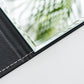 Close-up of folding makeup mirror edge with black PU leather frame and glass