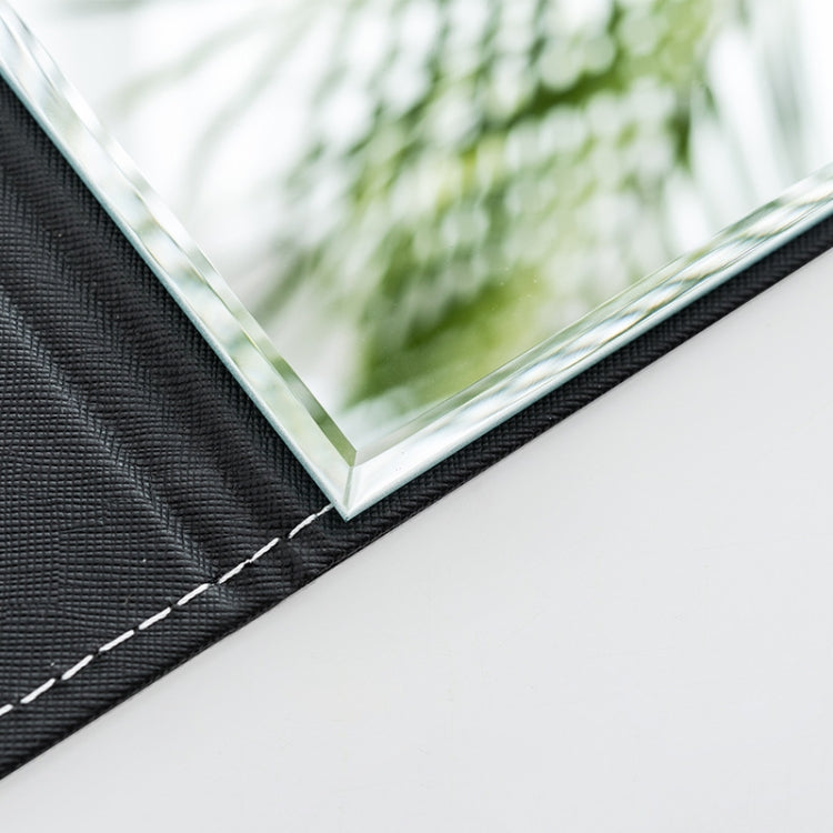 Close-up of folding makeup mirror edge with black PU leather frame and glass