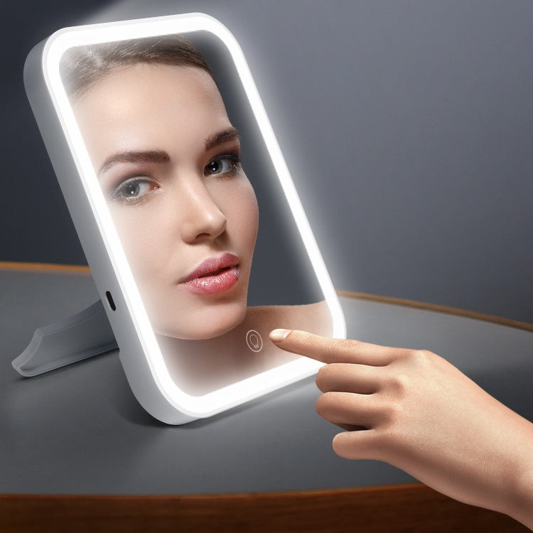 LED makeup mirror with bright light, white frame on desk, finger on control