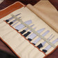Opened chef knife storage roll bag showing multiple knife slots and stitched leather trim