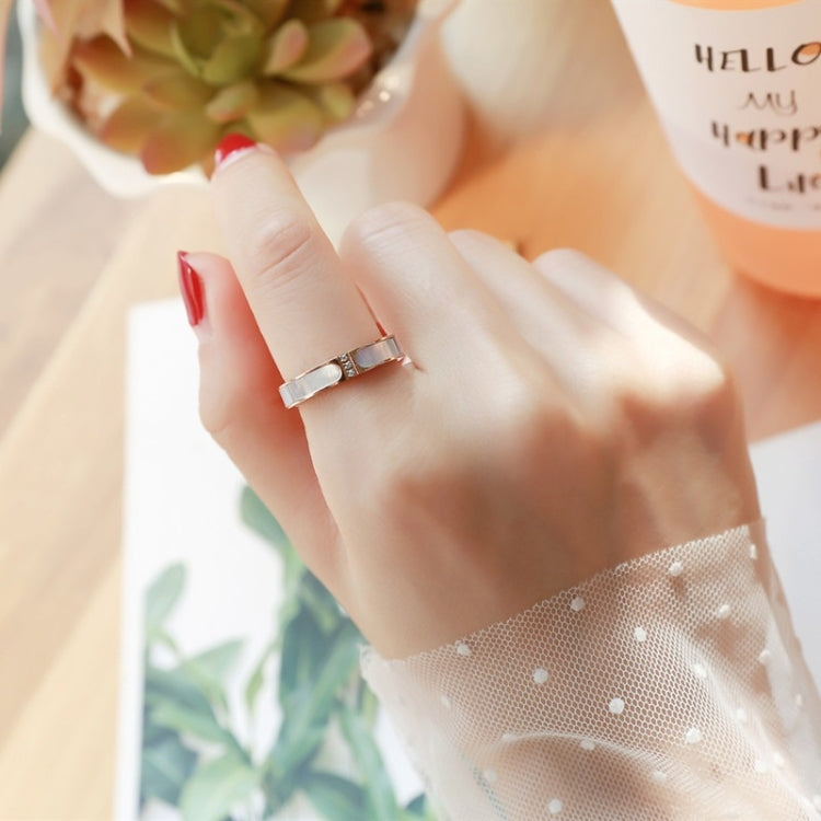 Silver-tone three-diamond ring on finger with square stone inlays on the band