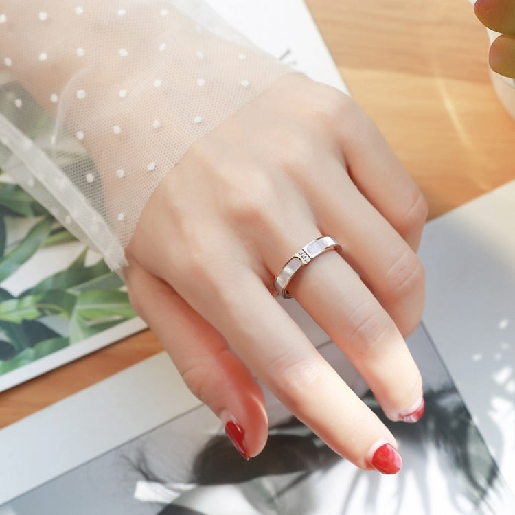 Silver-tone three-diamond ring worn on finger with square stone accents on band