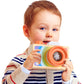 Child holding a wooden mini camera kaleidoscope toy with orange-ring lens and rainbow front