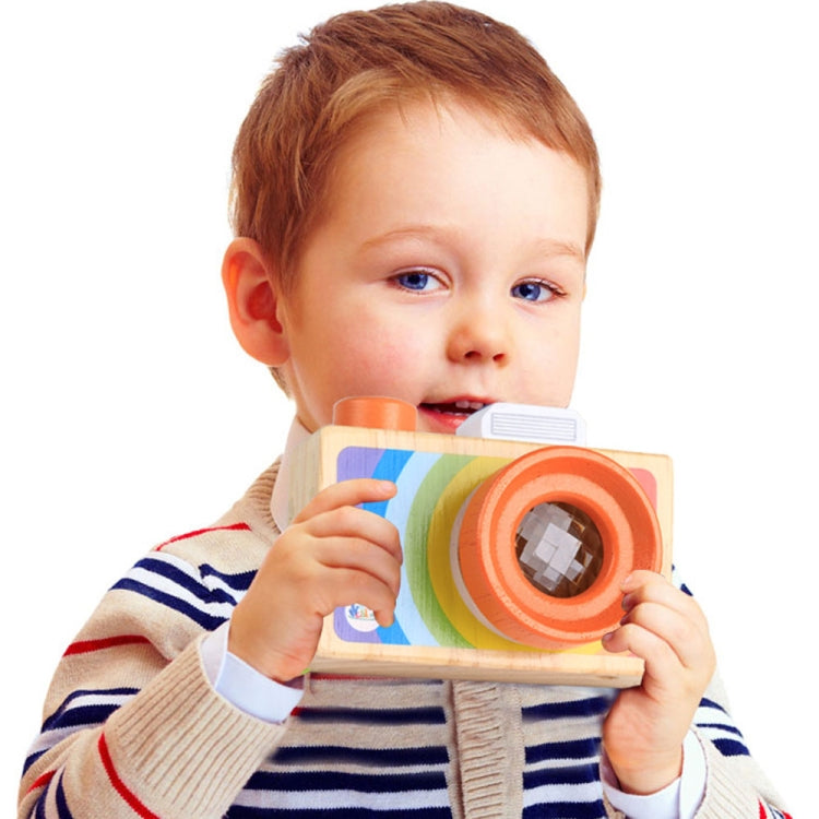 Child holding a wooden mini camera kaleidoscope toy with orange-ring lens and rainbow front