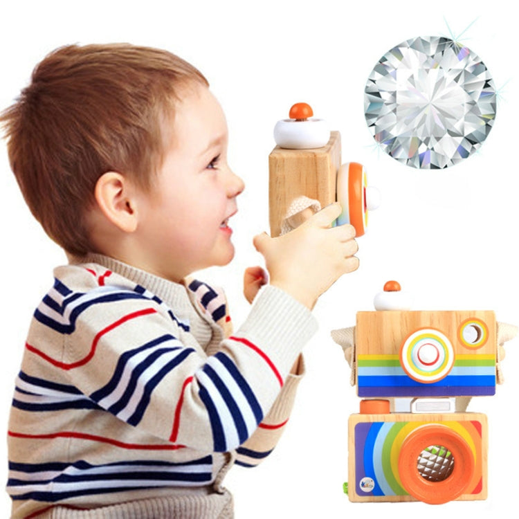 Child playing with a wooden camera kaleidoscope toy featuring orange-ring lens and rainbow panels