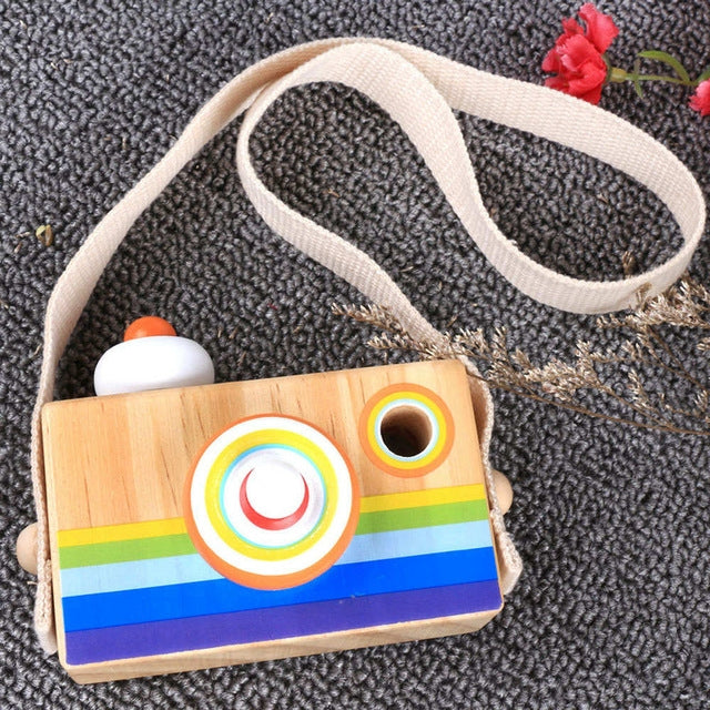 Wooden camera kaleidoscope toy with rainbow stripes and orange-ring lens on a strap
