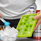 Green silicone ice cube tray held above ice cubes, showing 24 square mold grid