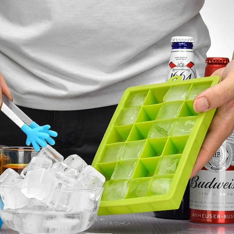 Green silicone ice cube tray held above ice cubes, showing 24 square mold grid