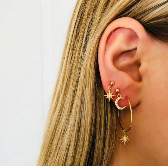 Gold-tone hoop earrings with dangling crescent moon, star, and small crystal charms