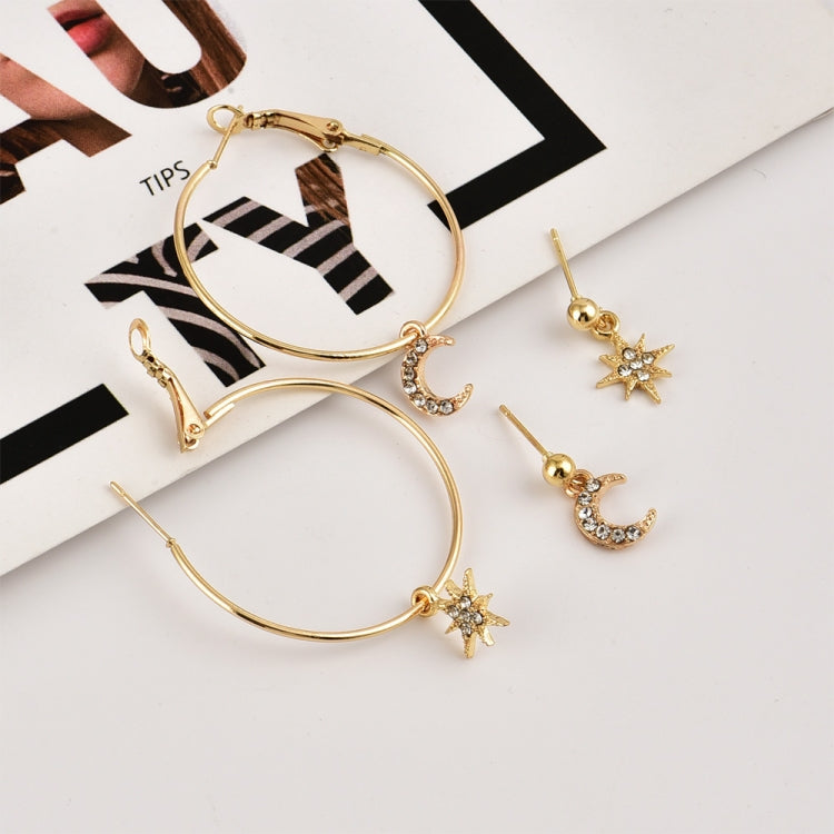 Gold-tone hoop earrings with crescent moon and star charms, arranged on a striped card