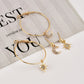 Gold-tone hoop earrings with crescent moon and star charms, laid on a paper display