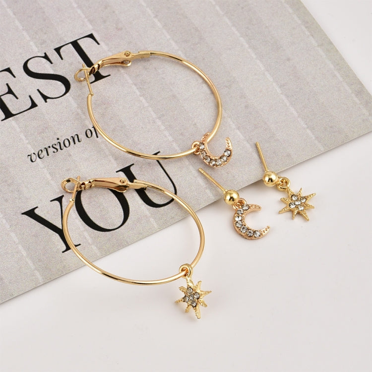 Gold-tone hoop earrings with crescent moon and star charms, laid on a paper display