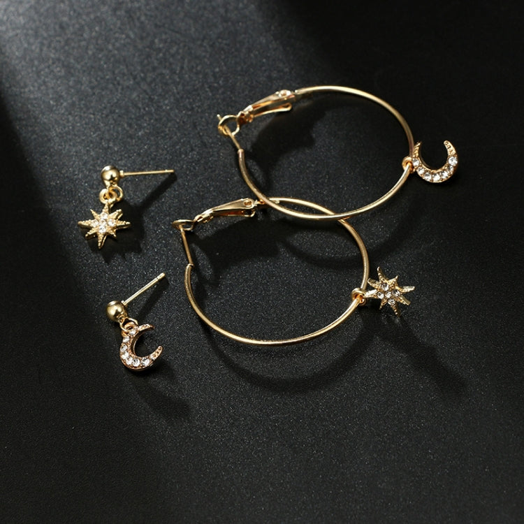 Gold-tone hoop earrings with star and crescent moon charms on a dark surface
