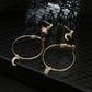 Gold-tone hoop earrings with crescent moon and star crystal charms on black fabric