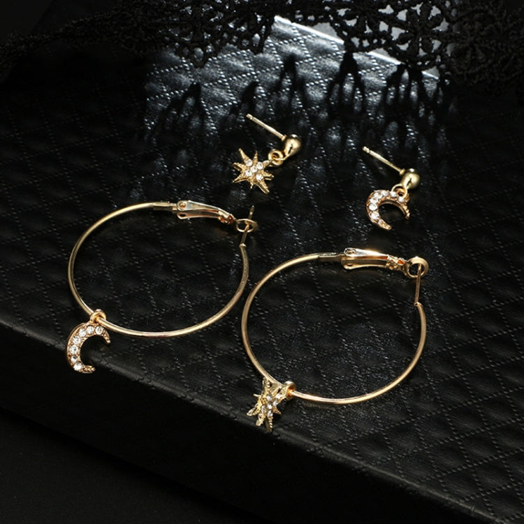 Gold-tone hoop earrings with crescent moon and star crystal charms on black fabric
