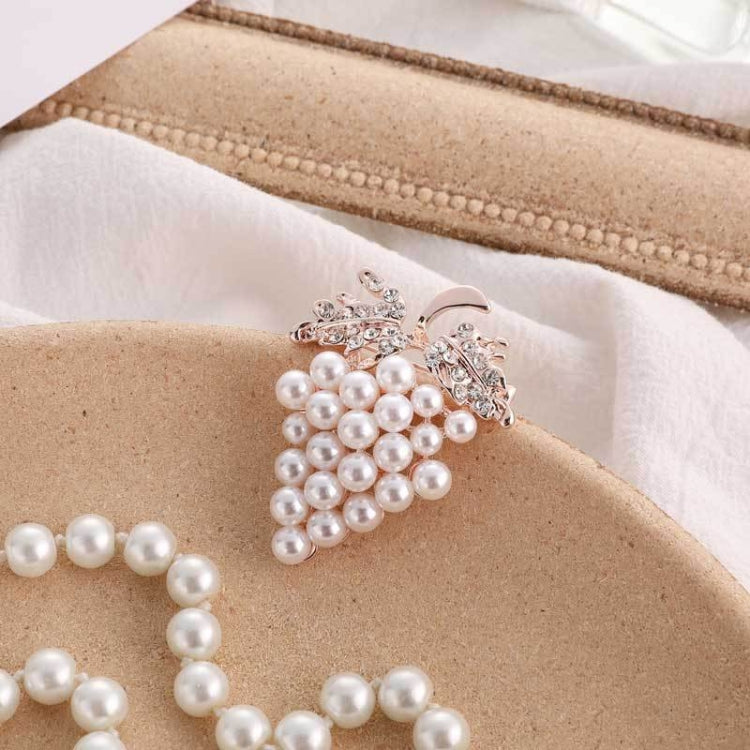 Grape-shaped pearl and rhinestone brooch close-up with rose-gold tone frame