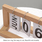 Close-up of wooden flipping desk calendar with metal rings and cards showing JAN 06