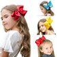 Kids ribbon hair bow clips in red, blue, and yellow worn in hair.