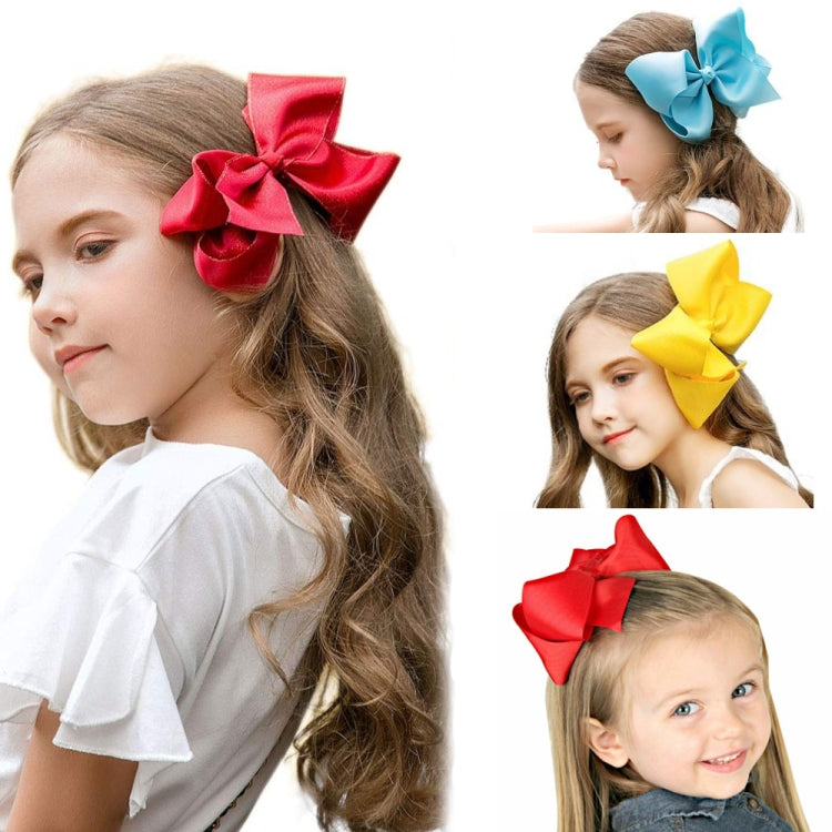 Kids ribbon hair bow clips in red, blue, and yellow worn in hair.