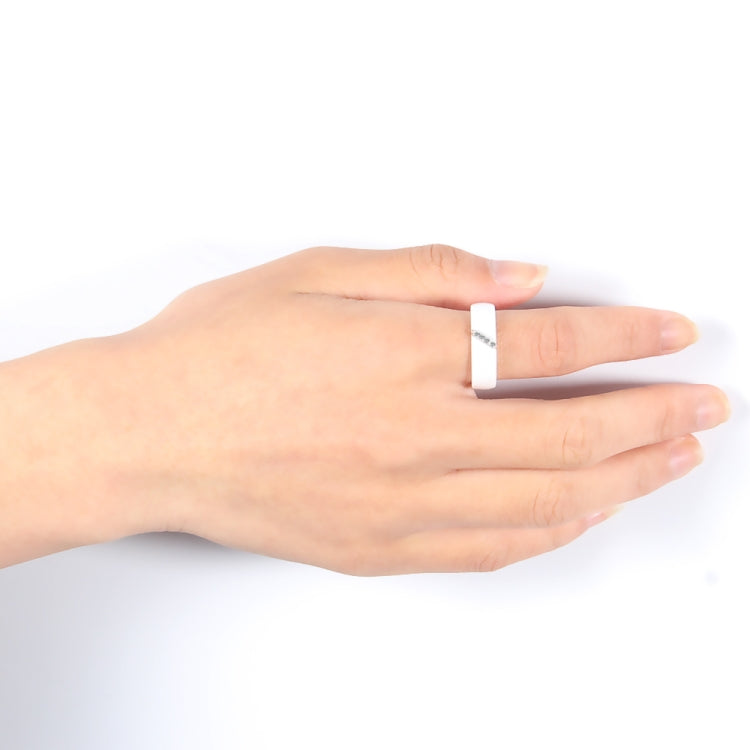 White ceramic ring on a hand, slim band with small crystal inlay