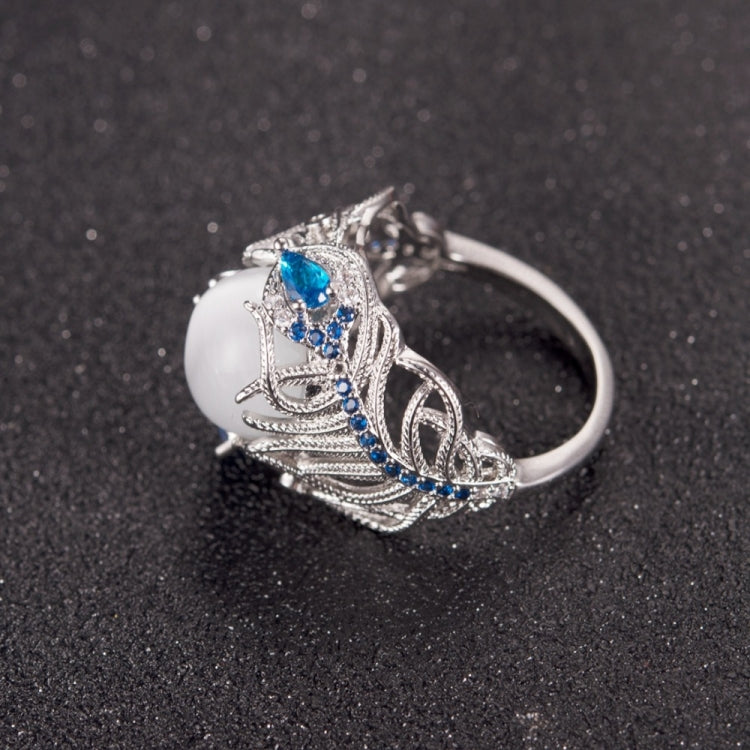 Silver-tone openwork ring with oval white stone and blue center gem, feather pattern
