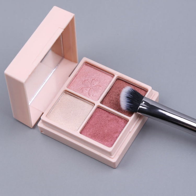 Makeup brush applying powder from a 4-pan compact palette with black handle