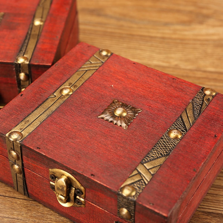 Red wooden jewelry box close-up: brass latch, studs, and top ornament