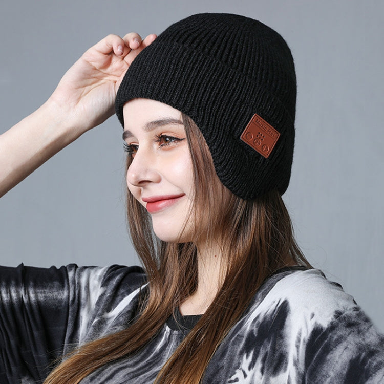 Black knit Bluetooth music hat with brown control patch, worn with long hair