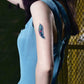 Single blue-green feather temporary tattoo sticker on upper arm