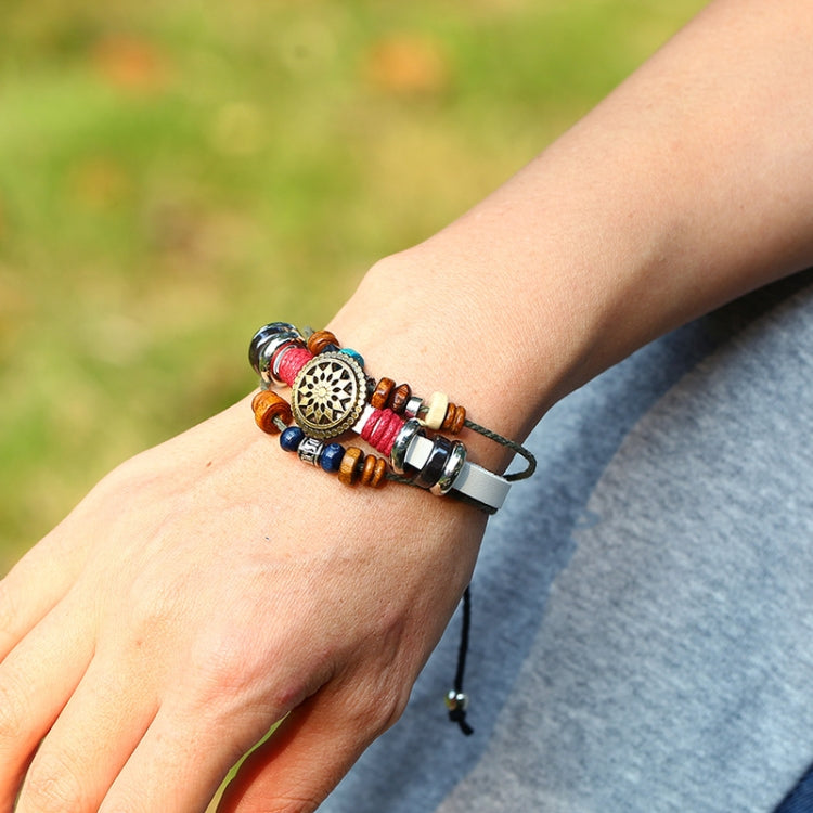 Beaded leather bracelet on wrist with circular charm, red blue beads, bronze-toned accents